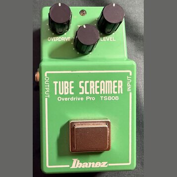 Zelený kytarový efekt s třemi černými ovládacími knoflíky. Na pedálu jsou bílé nápisy OVERDRIVE, TONE a LEVEL, dále velký nápis TUBE SCREAMER a pod n…