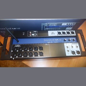 Černý digitální mixážní pult v rackovém provedení s modrým pruhem uprostřed. Na přístroji jsou nápisy Soundcraft Ui 16, lexicon, dbx a DiGiTech. Zaří…