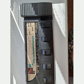 Šedý kytarový procesor s černým plastovým krytem, na kterém je vyražen nápis ZEEDER. Na horní části přístroje je uveden model 3030 ZOOM LAYER. Zaříze…