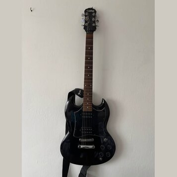 Černá elektrická kytara s tmavým hnedým hmatníkem a černým pickguardem. Na hlavě nástroje je bílý nápis Epiphone. Kytara má připevněný černý popruh s…