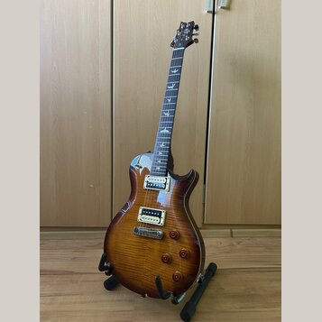Elektrická kytara s prohnutou deskou z plaménového dřeva v hnědém sunburst provedení. Na hmatníku jsou vyznačeny vložky ve tvaru ptáků a na hlavě je…