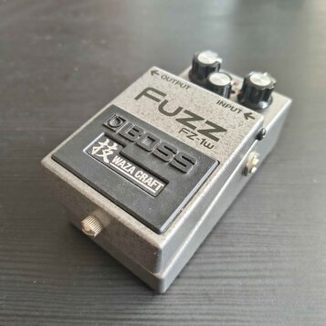 Kovový efekt pedál stříbrné barvy s černým spínacím tlačítkem. Na horní části je nápis FUZZ, označení modelu FZ-1w a značka BOSS. Na spínacím tlačítk…