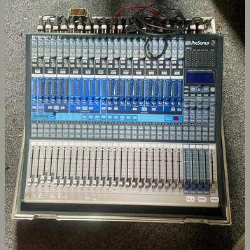 Šedý mixážní pult s modrými prvky a bílými popisky. V levém horním rohu je nápis STUDIOLIVE 24.4.2 a v pravém horním rohu logo PreSonus. Zařízení obs…
