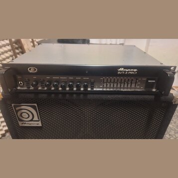 Černý basový zesilovač s nápisem Ampeg SVT-3 PRO umístěný na černé basové reproducing box s logem Ampeg. Přední panel zesilovače obsahuje ovládací kn…