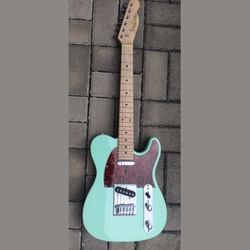 Světle zelená elektrická kytara typu Telecaster s javorovým hmatníkem a tmavě červeným šasi z vymyšleného perleťového plastu. Na hlavě je viditelné k…
