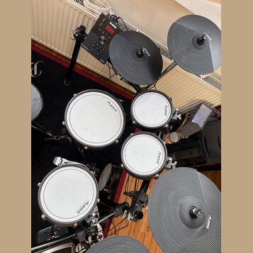 Elektronická bicí souprava značky Alesis. Na module je nápis Alesis a Crimson 1, na bubnech jsou viditelná loga Alesis. Souprava obsahuje čtyři bílé…