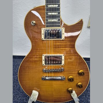 Elektrická kytara s trupem z plaménovky v žlutohnědém gradientu. Nástroj má dva humbuckery s krémovými rámečky, Tune-o-matic kobylku a stopbar struno…