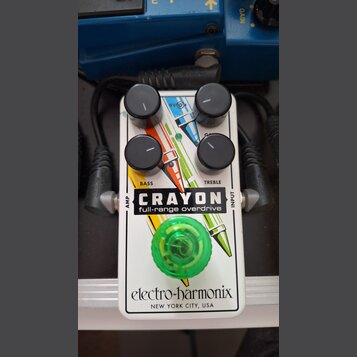 Bílý efekt pedál s nápisy CRAYON full-range overdrive a electro-harmonix NEW YORK CITY, USA. Pedál má čtyři černé ovládací knoflíky s popisky BASS a…