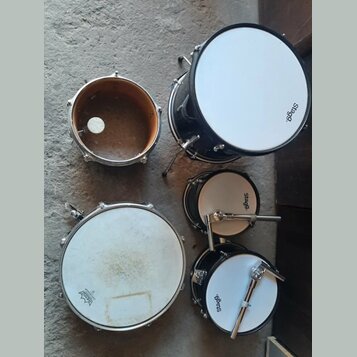 Sada pěti černých bubnů s bílými koženými membránami. Na třech z nich je vidět nápis Stagg. Jeden buben je bez membrány a v jeho vnitřku je vidět bíl…