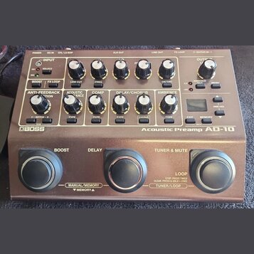 Hnědý kytarový předzesilovač s nápisem BOSS a Acoustic Preamp AD-10. Zařízení obsahuje řadu otočných potenciometrů, tlačítek a malý displej v pravé č…