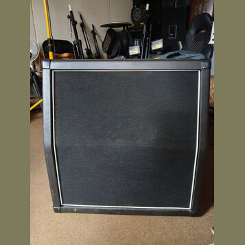 Černý kytarový nebo basový kombozesilovač s černou textilní maskou předu. Přístroj má hranatý tvar a je zakončen bílým lemem kolem masky. Povrch text…