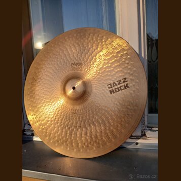 Kovový činel s výrazným kování povrchu v podobě drobných jamů. Na povrchu jsou černé nápisy „paiste 2002“, „JAZZ ROCK“ a v dolní části „HEAVY RIDE“.…