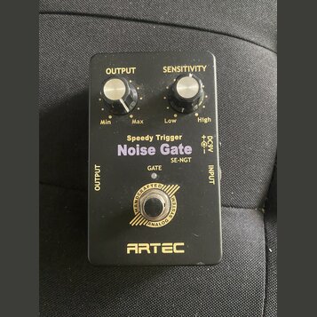 Černý efekt pedál s nápisy Speedy Trigger Noise Gate a SE-NGT. Na horní straně jsou dva ovládací knoflíky s popisky OUTPUT (Min, Max) a SENSITIVITY (…