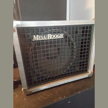 Kytarový kombozesilovač s černou síťovkou a stříbrným kovovým rámem. Na síťovce je umístěno bílé logo MESA/BOOGIE. Povrch kovového rámu vykazuje znám…