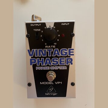 Kytarový efekt v stříbrném kovovém šasi s černým předním panelem. Na panelu jsou nápisy OUTPUT, INPUT, TONE, RATE a velký modrý text VINTAGE PHASER P…