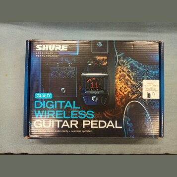 Fotografie znázorňuje krabici s produktem Shure GLX-D Digital Wireless Guitar Pedal. Na obalu je zobrazen černý bezdrátový pedál s červeným digitální…