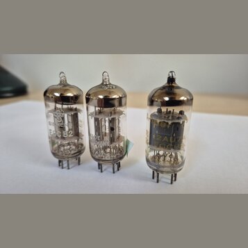 Tři skleněné elektronky s kovovými kontakty v dolní části. Na levé je nápis SIEMENS ECC 82, na prostřední nápis MADE IN GERMANY a na pravé nápisy 12A…