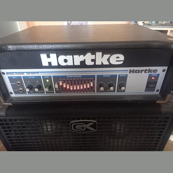 Černý basový zesilovač s bílým nápisem Hartke na horním krytu. Přední panel nese označení MODEL HA3500 350 WATTS a logo Hartke. Zesilovač je umístěn…