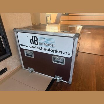 Hnědý transportní case s hliníkovými hranami a kovovými rohy. Na přední straně je bílý štítek s modrým logem dB TECHNOLOGIES a nápisem www.db-technol…