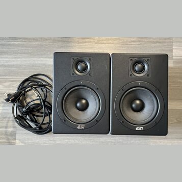 Dva černé studiové monitory s logem ESI v dolní části. Každý reproduktor obsahuje jeden výšký a jeden středně-nízký měnič. Vedle monitorů je srolovan…