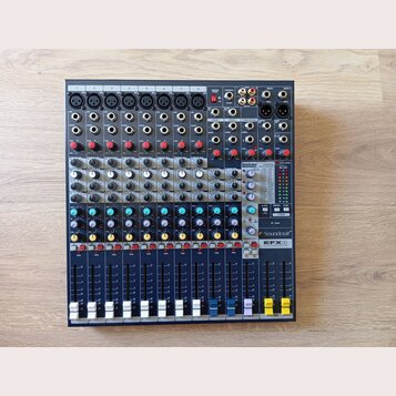 Modrý mixážní pult s šedým ovládacím panelem. Na přístroji jsou vidět nápisy exicon, Soundcraft a model EFX 8. V pravé části je digitální displej s t…