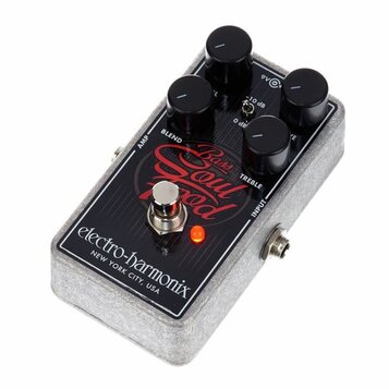 Šedý efekt pedál s povrchem z plstěného materiálu a černým ovládacím panelem. Na panelu je červený nápis Bass Soul Food a bílý nápis electro-harmonix…