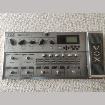 Šedý kytarový procesor s výrazným expresečním pedálem vpravo. Na zařízení jsou nápisy VOX, Valvetronix a ToneLab LE. Přední panel obsahuje řadu ovlad…