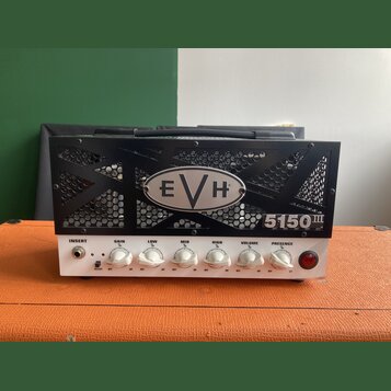 Černý kytarový zesilovač s kovovou mřížkou, na které je umístěno logo EVH a nápis 5150 III. Přední bílý panel obsahuje vstup INSERT, pět bílých otočn…