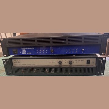 Dva rackové výkonové zesilovače naskládané na sebe. Horní zařízení je modré s černým horním krytem a nápisy PROFESSIONAL POWER AMPLIFIER, logo AG aku…