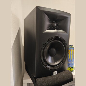 Černý studiový monitor s hornovým výstupem pro vysoké frekvence a kulatým basovým reproduktorem. V dolní části je viditelné bílé logo JBL. Reprodukto…