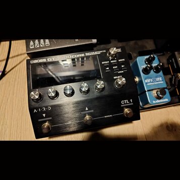 Černý kytarový procesor s kovovým povrchem a nápisem BOSS GT-1000CORE GUITAR EFFECTS PROCESSOR. Zařízení má displej, pět ovládacích knoflíků s čísly…