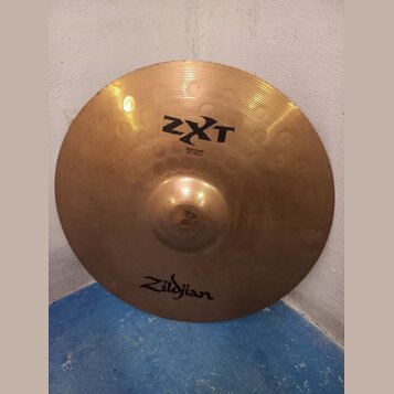 Kruhová mosazná činely s viditelným žebrováním. Na povrchu jsou nápisy ZXT, Rock Crash a 18"/45cm, v dolní části je logo Zildjian. Povrch vykazuje dr…