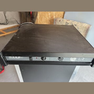 Černý výkonový zesilovač v kovovém šasi. Na předním panelu jsou nápisy DAS ELECTRONIC SERIES a L-2 HIGH PERFORMANCE POWER AMPLIFIER. Zařízení má vypí…
