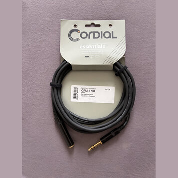 Černý audio kabel s pozlacenými konektory, upevněný na originálním papírovém obalu. Na obalu je nápis CORDIAL essentials a text Versatile fundamental…