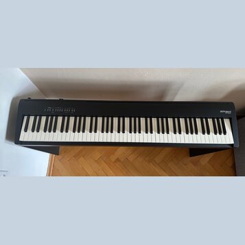 Černá digitální pianola na černém stojanu. Na pravé straně korpusu je bílý nápis Roland a pod ním model FP-30X. Na levé straně jsou umístěna ovládací…