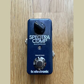 Tmavě modrý basový kompresor v kovovém provedení. Na přední straně jsou bílé nápisy SPECTRA COMP, BASS COMPRESSOR, TRUE BYPASS a logo tc electronic.…