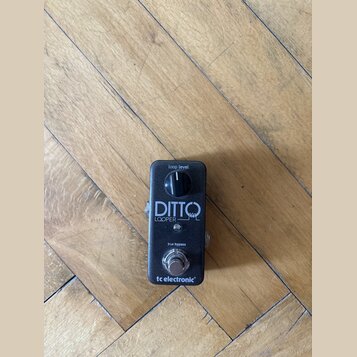 Černý kytarový pedál s nápisy „loop level“, „DITTO LOOPER“ a „true bypass“. Ve spodní části je umístěno logo „tc electronic“. Zařízení má jeden ovlád…