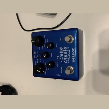 Modrý efekt pedál značky NUX s nápisem Solid Studio I.R.E. Power Amp Simulator. Zařízení má pět černých otočných ovladačů a dva stomečkové spínače oz…