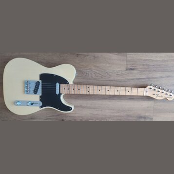 Elektrická kytara s krémovým korpusem, černým pickguardem a světle hnědým hmatníkem. Na hlavě krku je nápis Fender TELECASTER. Nástroj vykazuje čistý…