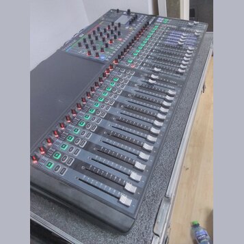 Šedočerný mixovací pult s posuvníky a řadou ovládacích knoflíků. V levém horním rohu je bílý nápis Soundcraft a vedle něj označení modelu SX. Zařízen…