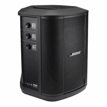 Černý reproduktor s kovovou ochrannou mřížkou. Na pravé straně je umístěno stříbrné logo BOSE. Vlevo se nacházejí tři oválné ovládací knoflíky, u kte…