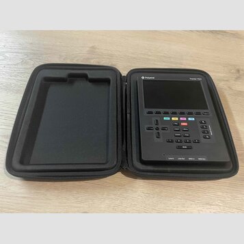 Černý přenosný sekvencer Polyend Tracker Mini v černém zipovém pouzdře. Na horní hraně přístroje jsou nápisy Polyend a Tracker Mini. Ovládací panel o…