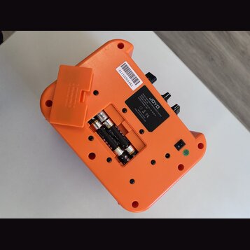 Zadní strana oranžového efekt pedálu značky JOYO. Na černé štítku je nápis „JOYO MINI PEDAL FOR ELECTRIC GUITAR MODEL: JA-01 POWER SUPPLY: 9V DC - (c…