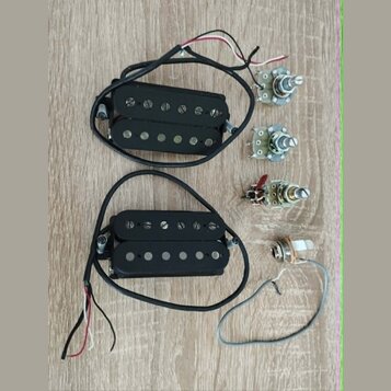 Dva černé humbuckery s černými kryty snímačů a viditelnými polosférickými póly. K oběm snímačům vedou černé kabely s barevnými vodiči. Vedle nich jso…