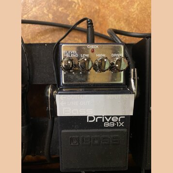 Černý efekt pedál s nápisy Driver BB-1X a logo BOSS. Na horní části jsou čtyři ovládací knoflíky s popisky LEVEL, BLEND, LOW, HIGH a DRIVE a kontrolk…