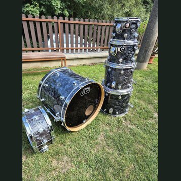 Sada bubnů s tmavým, mramorovaným povrchem v odstínech černé a šedé. Na rezonanční kože a na tomarech je viditelné logo „dw drums“. Sada obsahuje bas…