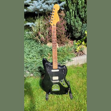 Černá elektrická kytara s černým pickguardem a světle hnědým hmatníkem. Na hlavě je viditelné logo Fender a nápis Japan. Nástroj má dva snímače, tři…