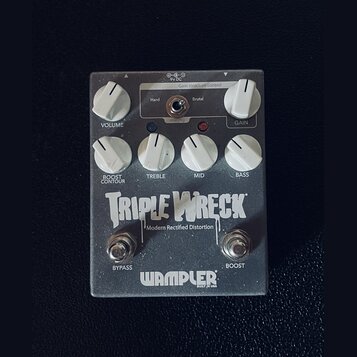 Stříbrný efekt pedál s nápisy TRIPLE WRECK a Modern Rectified Distortion. V dolní části je logo WAMPLER s doplňkem BUILT IN USA. Pedál má šest bílých…
