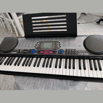 Černý digitální klavír značky CASIO, model CTK-551 s nápisem TOUCH RESPONSE. Nástroj má bílé a černé klávesy, dvě integrovaná kulatáh reproduktory po…