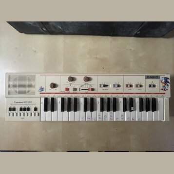 Bílý přenosný klávesový syntezátor s nápisy Casio, Casiotone MT-60 a logem Sonic the Hedgehog. Přístroj obsahuje ovládací prvky v horní části, včetně…